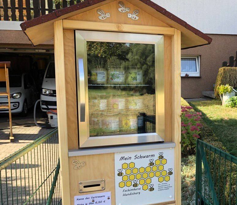 Selbstgebauter Honig-Automat, die sogenannte Kasse des Vertrauens, mit Wabenlogo und Preisschild