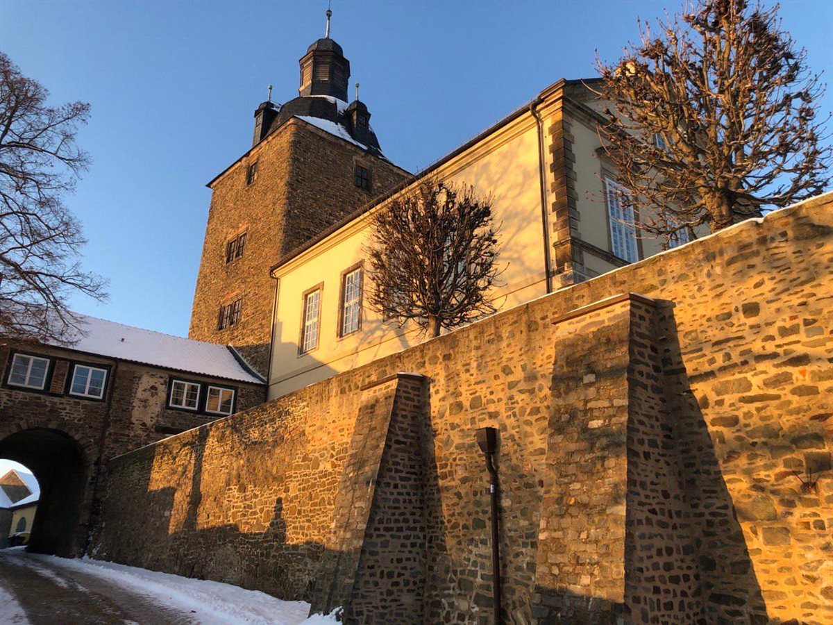 Schloss Hundisburg mit steinerner Mauer im Winter bei goldener Abendsonne